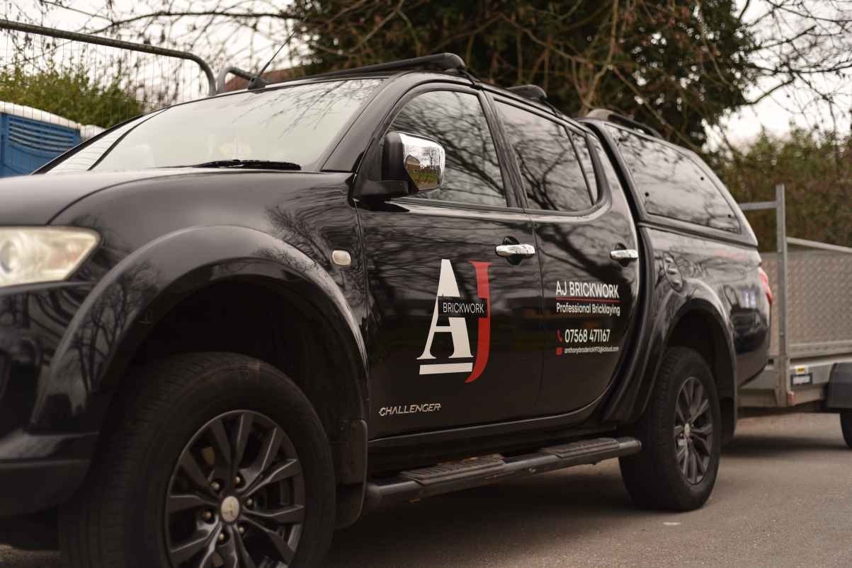 The AJ Brickwork branded pickup truck and trailer on site in Manchester