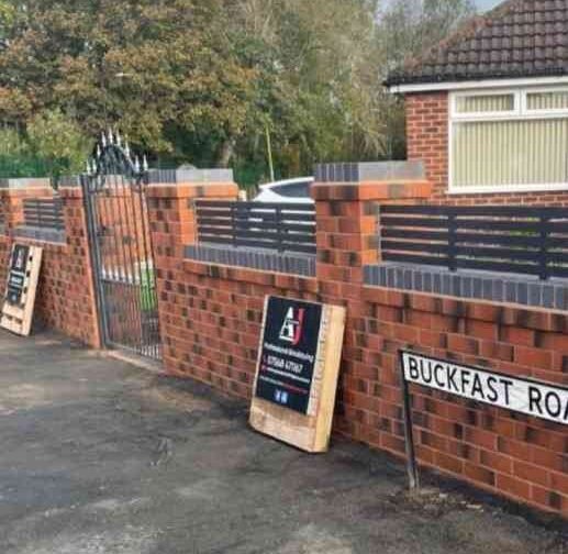 Brick wall with railings and an AJ Brickwork sign board