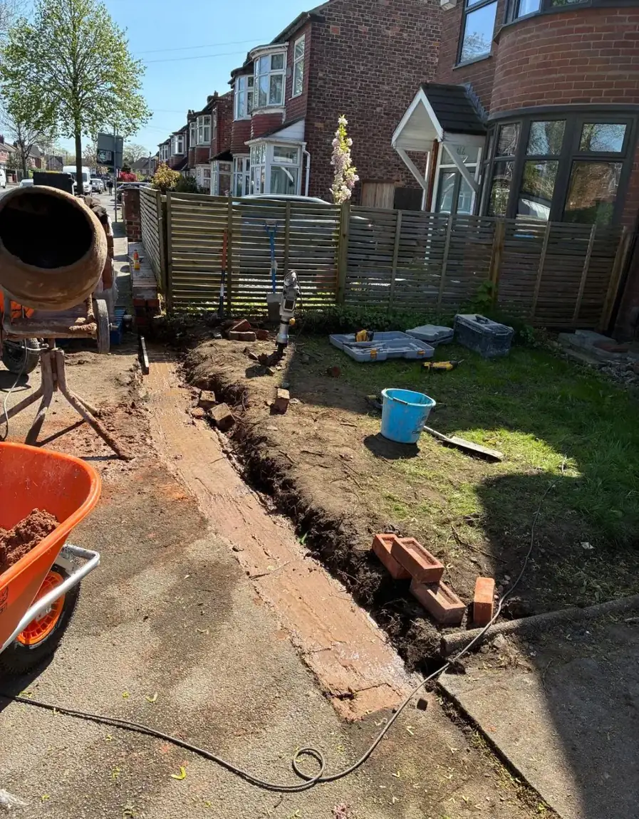 Footings dug along a front boundary ready for a new brick wall, with cement mixer on site
