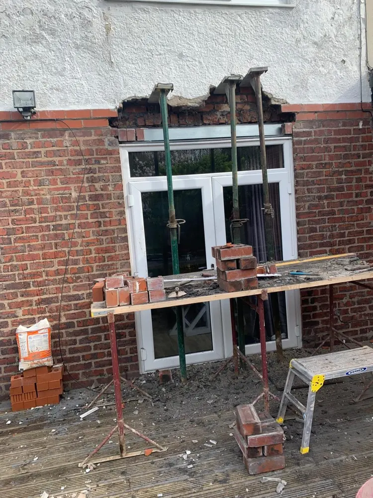 Props supporting the brickwork above a doorway while a lintel is replaced
