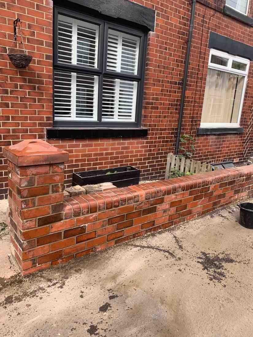 Low red brick wall with pier and coping, built by AJ Brickwork in Manchester