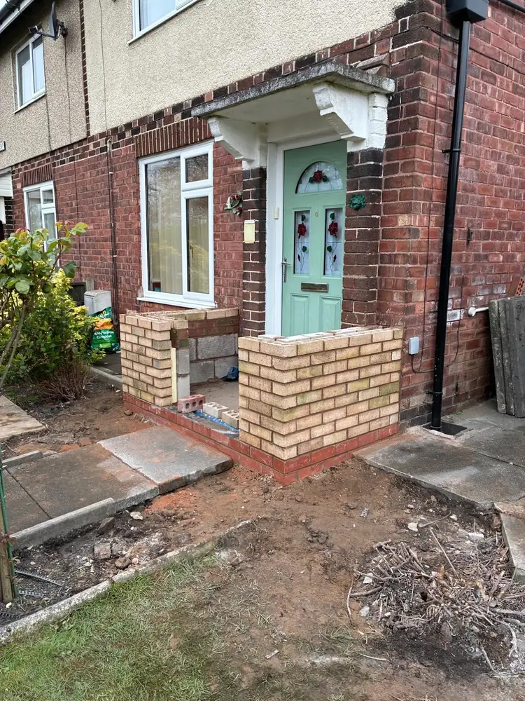Porch walls built up in buff brick with a red brick plinth course
