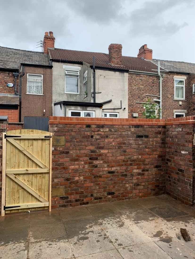 Brick boundary wall with a timber gate, built by AJ Brickwork in Manchester